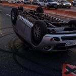 Carro capotado em rodovia no DF após acidente por embriaguez, com viaturas policiais ao redor.