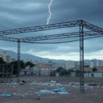 Estrutura danificada por raio perto de palco em ato político em Belo Horizonte, com céu tempestuoso e arquitetura local.