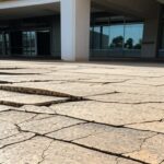 Calçada quebrada e inacessível em frente a prédio público em Brasília, expondo negligência em acessibilidade no DF.