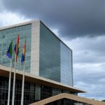 Fachada da CLDF em Brasília com bandeira LGBTQIAPN+ ao vento, representando Programa Reconhecer e vulnerabilidade no DF.