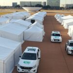 Centro de acolhimento para pessoas em situação de rua no Plano Piloto de Brasília, com tendas e veículos oficiais.