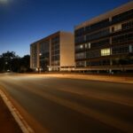 Rua escura no Plano Piloto, Brasília, durante interrupção programada de energia, com edifícios modernos ao fundo.