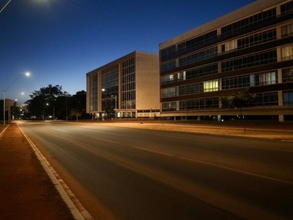 Rua escura no Plano Piloto, Brasília, durante interrupção programada de energia, com edifícios modernos ao fundo.