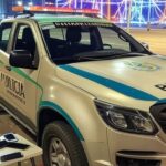 Viatura da Polícia Militar do DF na saída do Carnaval, com confetes e decorações festivas ao fundo.