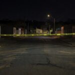 Rua em Sobradinho isolada por fita policial após briga fatal, com marcas no chão e casas ao fundo.