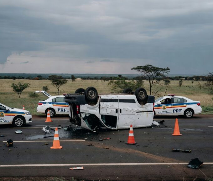 Cena de acidente com van tombada na BR-020 em Planaltina, com viaturas da polícia rodoviária federal ao fundo.