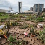 Horta urbana em Brasília com solo seco e edifícios ao fundo, representando debates sobre melhorias na agricultura em meio a crises no DF.