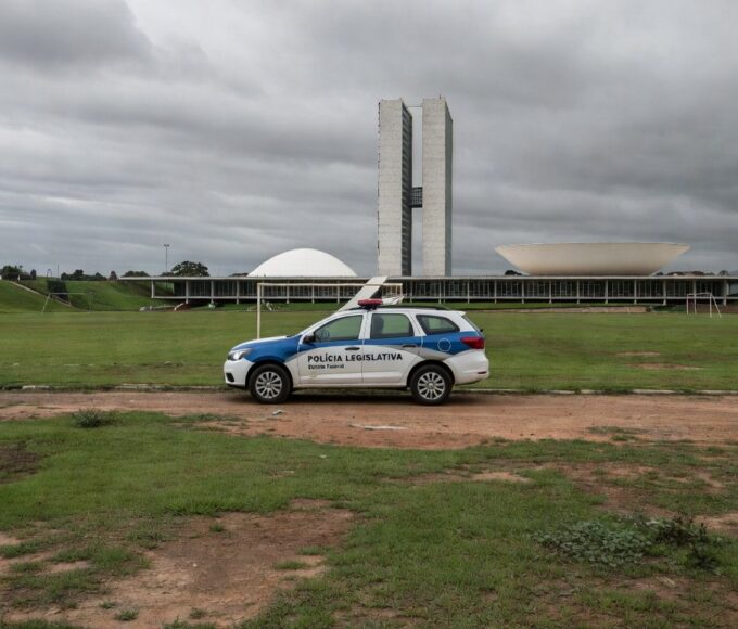 Viatura da polícia legislativa em rua de Brasília com cena de crime ao fundo, destacando escalada de violência no DF.