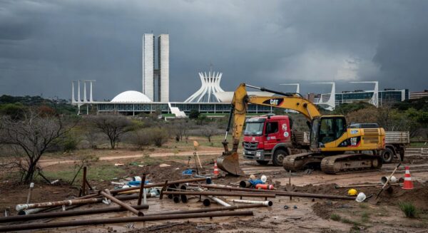 Paisagem seca no DF com reservatório vazio e obras de saneamento em Brasília, destacando crise hídrica e atrasos.