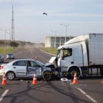 Cena de acidente de trânsito em avenida de Brasília, com veículos danificados e sinalização, representando estudo sobre condutores em acidentes fatais no DF.