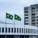 Fachada da Câmara Legislativa do DF com hospital público deteriorado ao fundo, destacando falhas na saúde pública em Brasília.