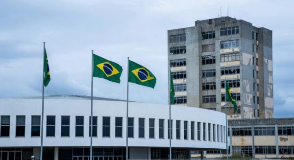 Fachada da Câmara Legislativa do DF com hospital público deteriorado ao fundo, destacando falhas na saúde pública em Brasília.