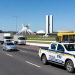 Viatura da PRF ao lado de ônibus em rodovia de Brasília, ilustrando prisão de homem por assédio a mulheres.
