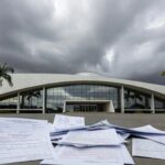 Fachada da CLDF em Brasília com elementos simbólicos de homenagem e crise no setor de seguros.