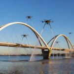 Ponte JK em Brasília com drones e hidrojateamento limpando arcos sobre o Lago Paranoá.