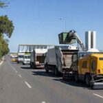Equipamentos de zeladoria urbana em rua de Brasília, com arquitetura moderna ao fundo.