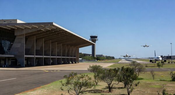 Aeroporto de Brasília com arquitetura moderna e aviões na pista, representando leilão governamental.
