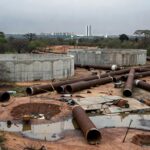 Obras de combate à escassez hídrica no DF, com canteiro de construção e paisagem seca em Brasília.