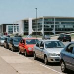 Ruas de Brasília com carros estacionados e arquitetura modernista, contexto de guardadores de carros.